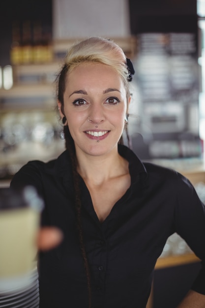 Portrait of waitress standing with disposable coffee cup