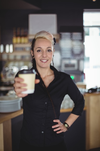 Foto gratuita ritratto della cameriera di bar che sta con la tazza di caffè eliminabile