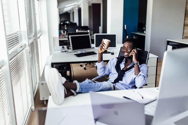 Портрет белого бизнесмена, работающего над проектом в современном офисе, держа кофе и расслабляясь.
