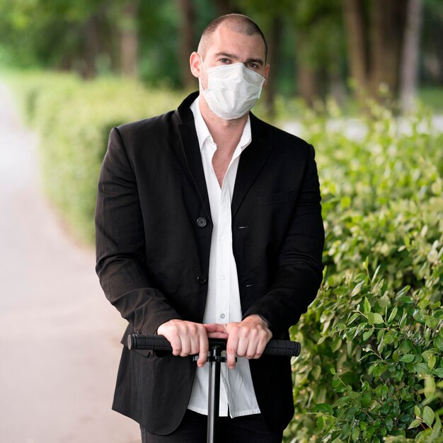 Portrait with medical mask riding scooter