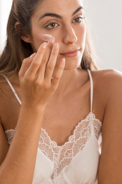 Portrait of woman applying cream on her face