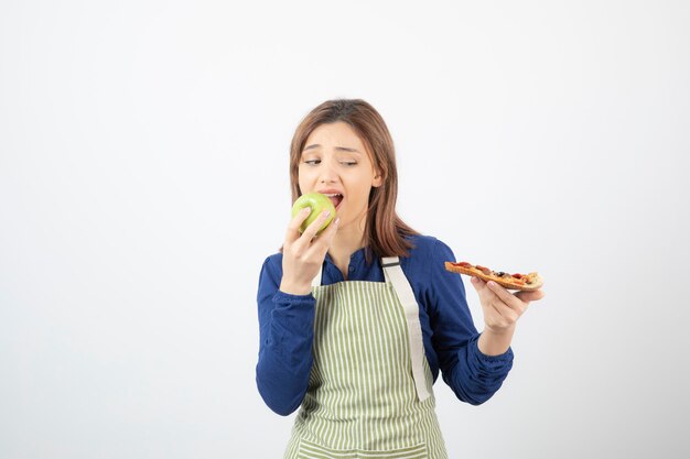 ピザを見ながら青リンゴを食べるエプロンの女性の肖像画