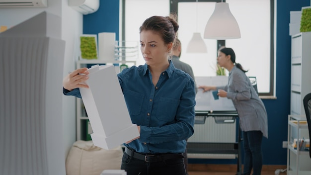 Portrait of woman architect analyzing building model to create urban project structure. Industrial contractor looking at maquette layout to plan and design construction development.