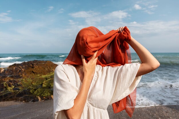 portrait of woman at the beach covering her face with veil