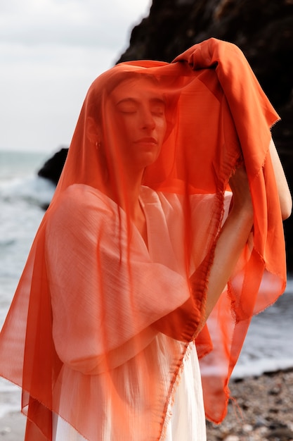 Ritratto di donna in spiaggia che copre il viso con il velo