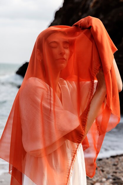 portrait of woman at the beach covering her face with veil