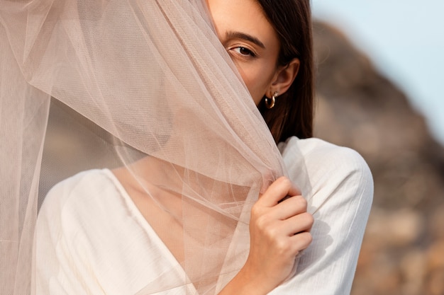 Free photo portrait of woman at the beach hiding her face behind veil