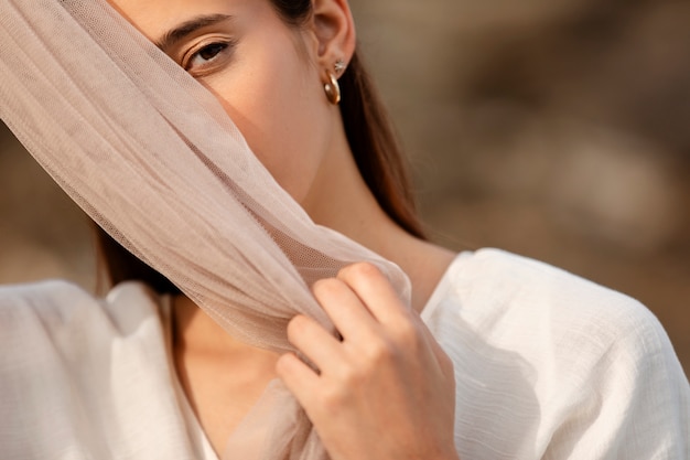 Portrait of woman at the beach hiding her face behind veil