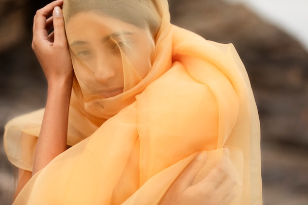 Free photo portrait of woman at the beach with face covered by veil