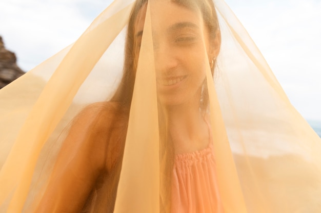 Ritratto di donna in spiaggia con il viso coperto da velo