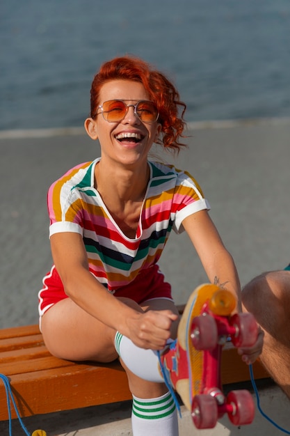 Foto gratuita ritratto di donna in spiaggia con pattini a rotelle in stile anni '80