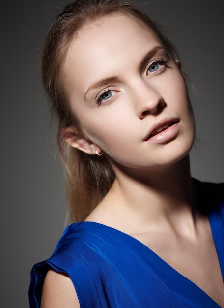 Portrait of a woman in a blue dress isolated on a grey background.