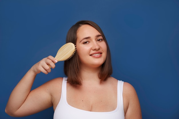 Free photo portrait of woman brushing her hair as part of her beauty regimen