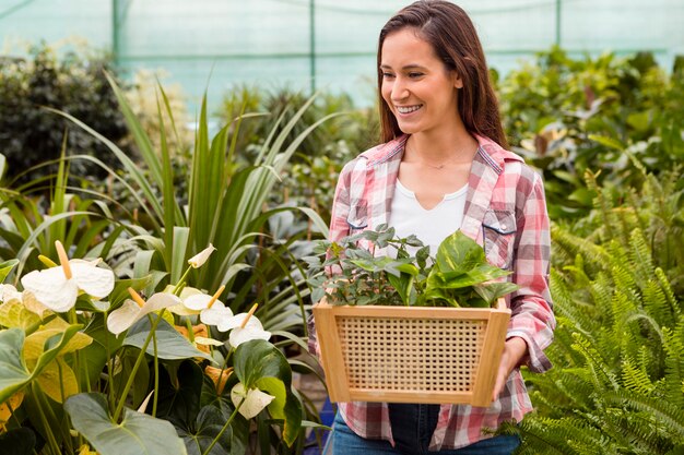 Portrait of woman carrying basket in greenhouse