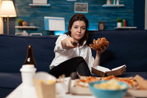 Portrait of woman changing channels using remote watching entertainment movie series