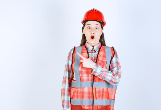 Portrait of woman construction worker pointing on white background. 