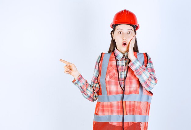 Portrait of woman construction worker pointing on white background. 
