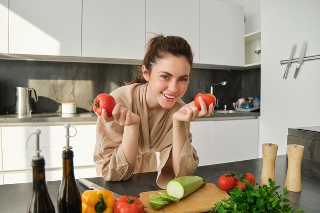 Portrait of woman cooking at home in the kitchen holding tomatoes preparing delicious fresh meal