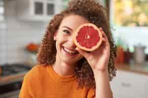 Free photo portrait of woman covering her eye with grapefruit