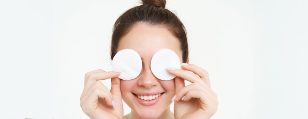 Foto gratuita ritratto di una donna che copre gli occhi con cuscinetti di cotone che pulisce la pelle dopo il trucco che usa quotidianamente