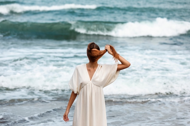 Портрет женщины, закрывающей лицо волосами на пляже