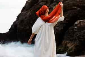 Free photo portrait of woman covering her face with veil at the beach