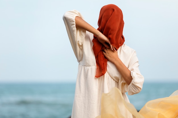 Портрет женщины, закрывающей лицо вуалью на пляже