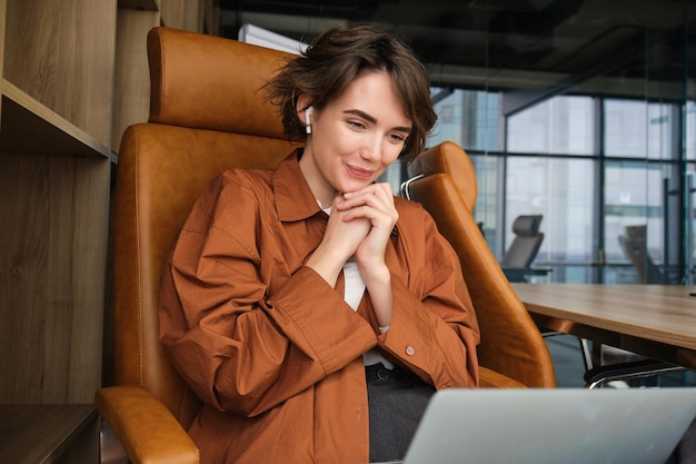 Free photo portrait of woman discussing work project during online meeting looking at laptop working in office