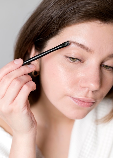 Free photo portrait woman doing her eyebrows