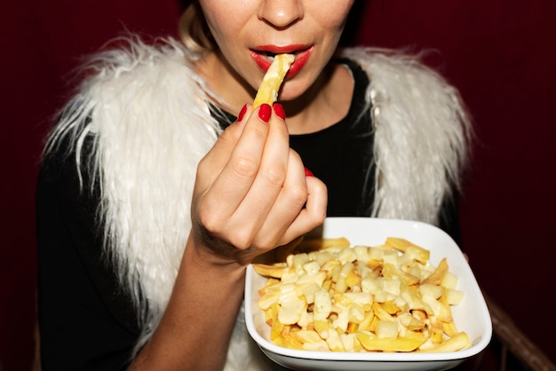 Portrait of woman eating a dish of poutine