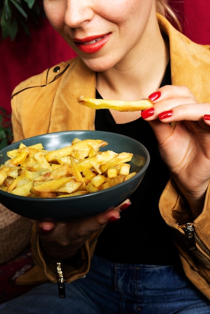 Free photo portrait of woman eating a dish of poutine