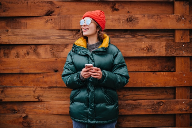 Portrait of woman in emerald green coat on wooden wall