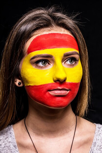 Портрет поклонника сторонника женского лица сборной Испании с раскрашенным лицом флага, изолированным на черном фоне. Поклонники эмоций.