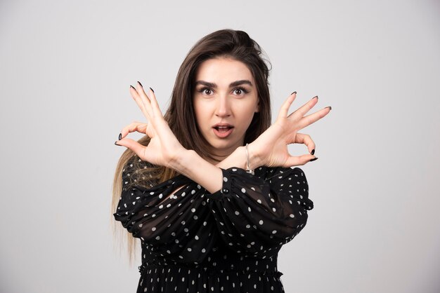 Portrait of woman giving ok sign on gray.