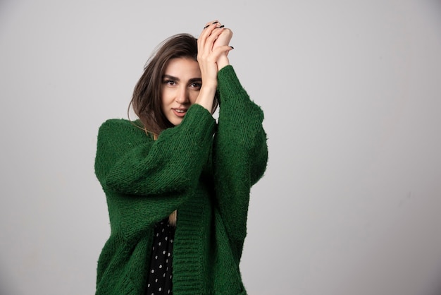 Portrait of woman in green jacket standing on gray.