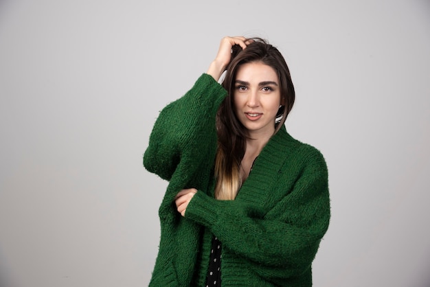 Portrait of woman in green jacket touching her hair.