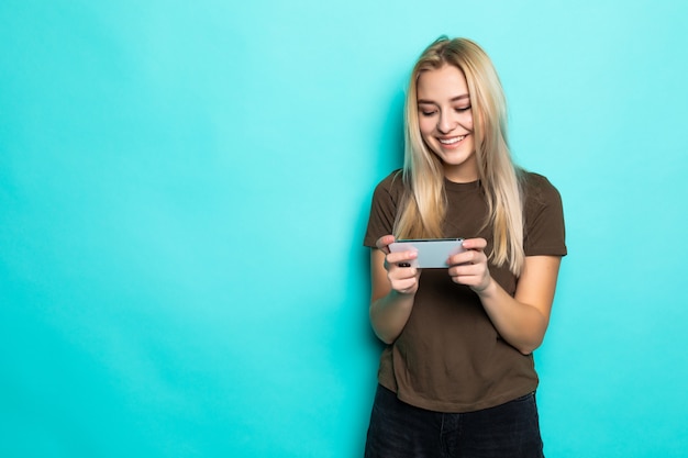 Portrait woman having fun game device gadget isolated over blue wall