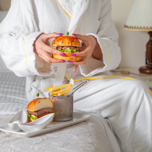 Портрет женщины едят гамбургер в халате