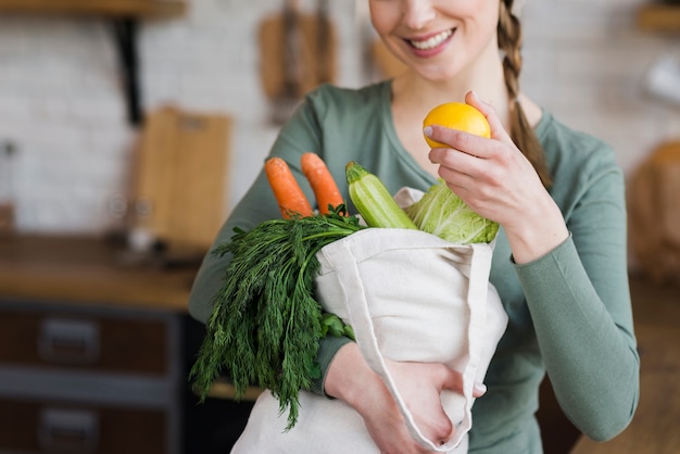 Portrait of woman holding bag with fresh vegetables