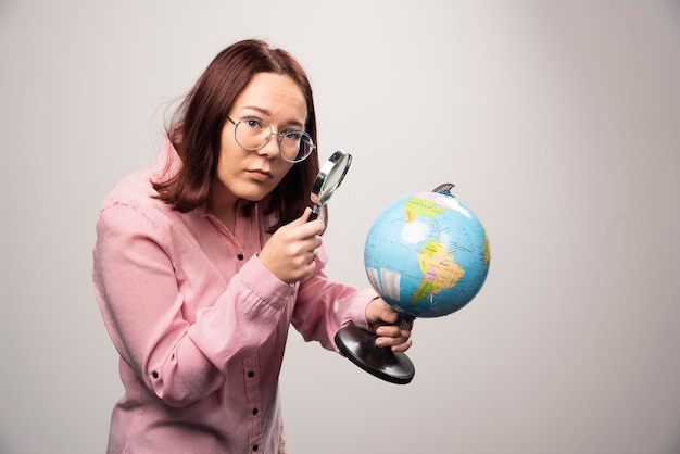 Portrait of woman holding a magnifying glass and Earth globe. High quality photo