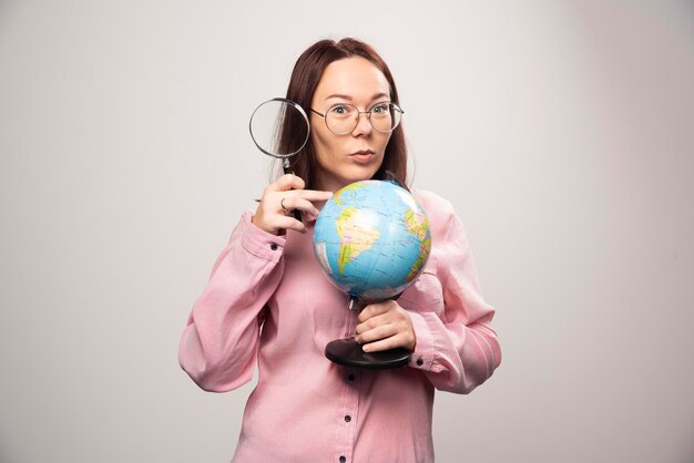 Portrait of woman holding a magnifying glass and Earth globe. High quality photo