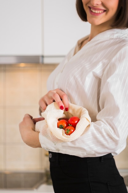 Free photo portrait of woman holding organic tomatoes