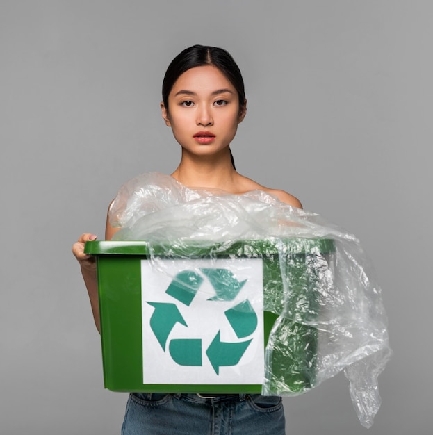 Free photo portrait of woman holding a recycle bin