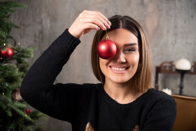 光沢のあるクリスマスボールを保持している女性の肖像画。