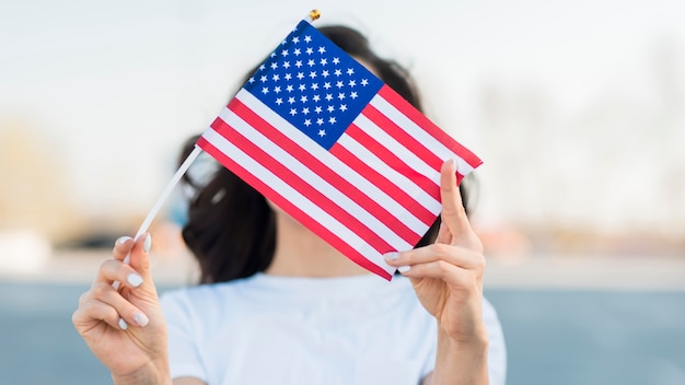 Portrait of woman holding usa flag over face