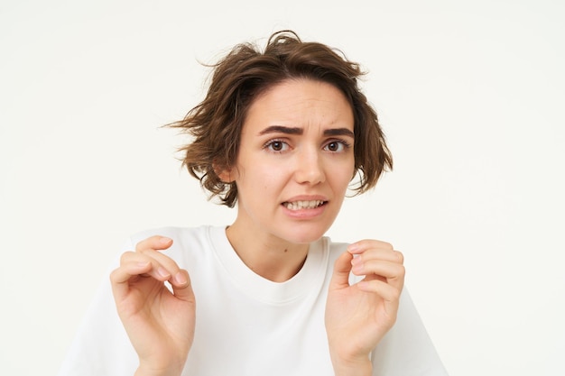 Free photo portrait of woman jumps from fear looks disgusted cringe from something express dislike or aversion