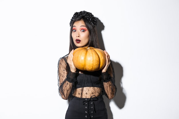 Free photo portrait of woman lifting heavy pumpkin, getting ready for halloween