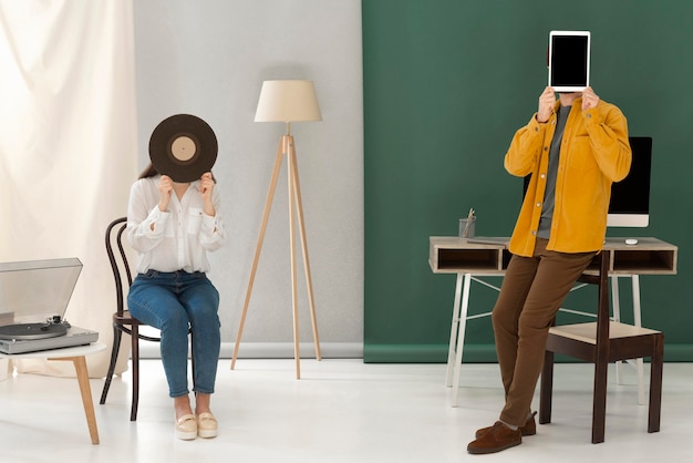 Портрет женщины, слушающей музыку на пикапе, и мужчина, использующий планшет