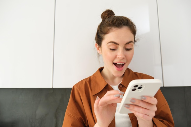 Free Photo portrait of woman looking with excitement at smartphone found something at online shopping app order