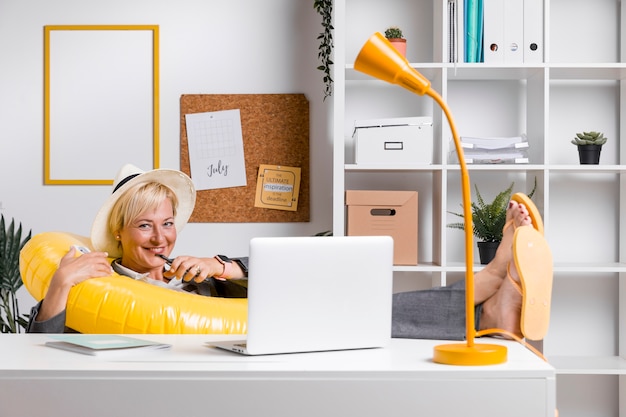 Portrait of woman in office prepared for summer holiday